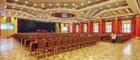 A large hall with rows of chairs and a stage, likely for events or conferences.