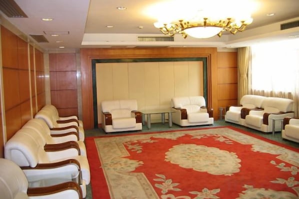 A hotel room with a large red carpet, multiple white leather sofas, and a chandelier. - Jinxiu Hotel (Shanghai)