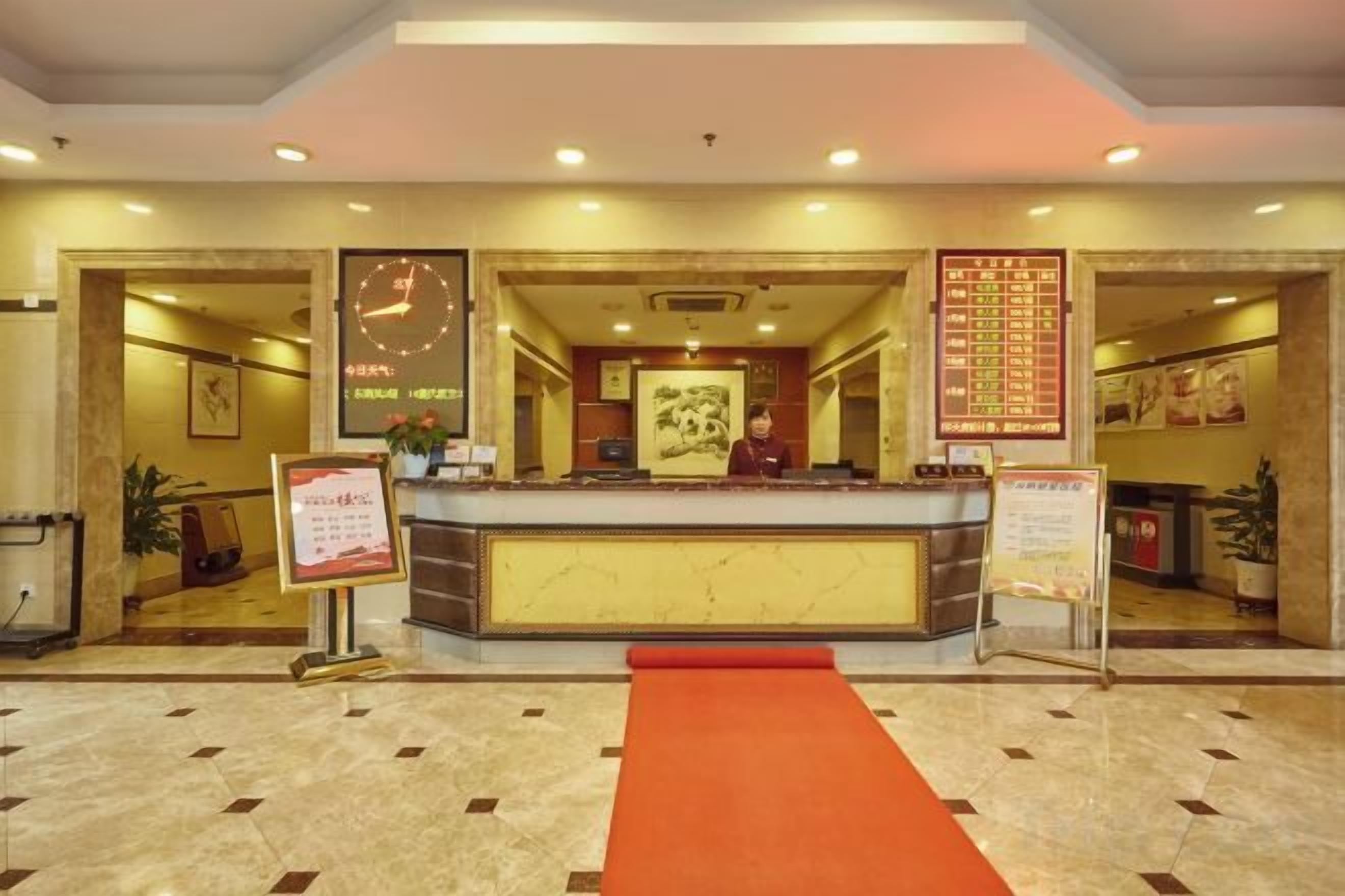 A hotel reception area with a reception desk, a red carpet, and a wall with a menu.