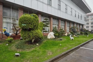 A building with a well-maintained lawn, various topiary sculptures, and a parking lot. - Jinxiu Hotel (Shanghai)
