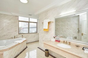 A modern bathroom with a large bathtub, a sink, and a mirror. - Jinxiu Hotel (Shanghai)