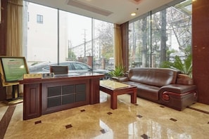 A lobby with a reception desk, a leather sofa, and a coffee table. - Jinxiu Hotel (Shanghai)