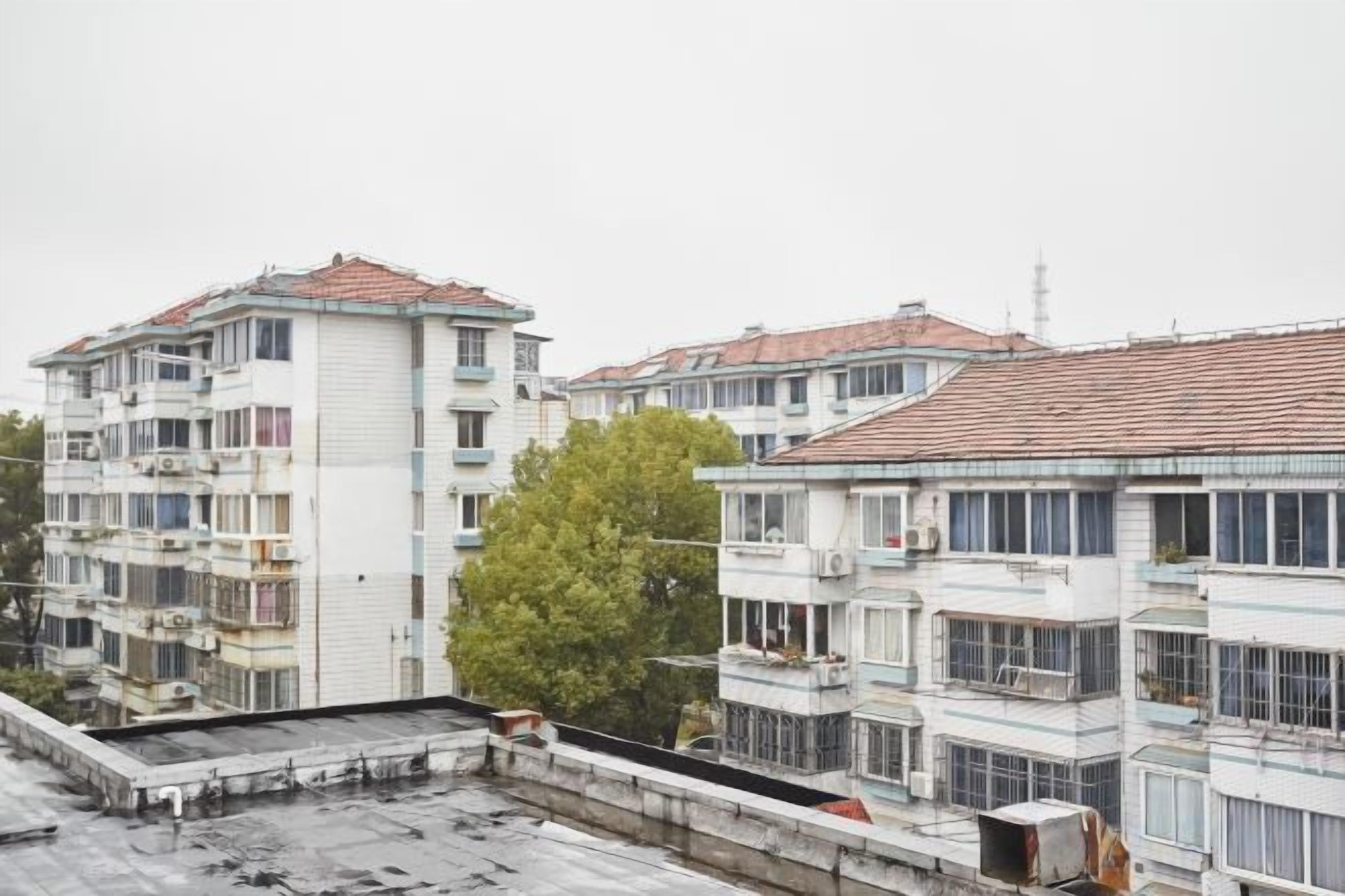A multi-story residential building with balconies, a flat roof, and a visible antenna.