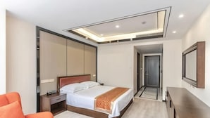 A modern hotel room with a bed, a desk, a chair, a mirror, and a ceiling light fixture. - Jinxiu Hotel (Shanghai)