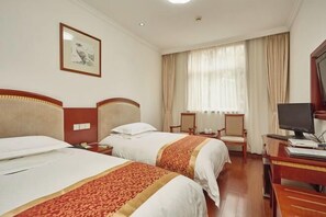 Une chambre d’hôtel avec deux lits, un bureau avec un ordinateur, une chaise et une fenêtre avec des rideaux.