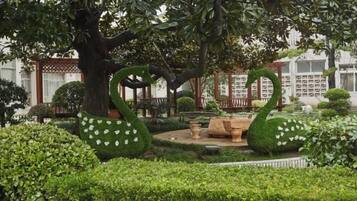 Un jardín con un topiario con forma de cisne, una fuente y setos cuidados.
