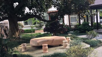 A garden with a stone bench, potted plants, and a gazebo.