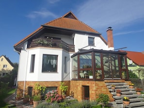 A two-story house with a red-tiled roof, a glass conservatory, and a brick facade. - Schmidtappartement (Berlin)