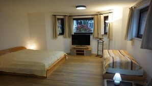 Une chambre avec deux lits, une télévision et une fenêtre avec des rideaux.