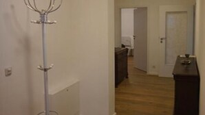 Un couloir avec un porte-manteau, une porte et une commode.