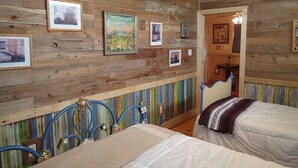 Quarto com paredes de madeira, uma cama, uma cadeira e um ventilador de teto.
