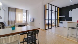 Eine moderne Wohnung mit Essbereich, Küchenzeile und Wohnraum mit großem Fenster.