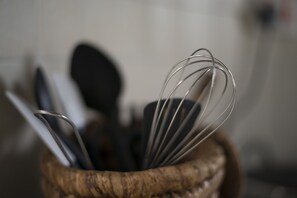 A close-up of a wooden utensil holder with metal whisks and a spoon. - Nyati Hill Cottages (Nairobi)