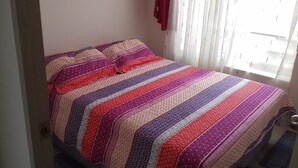 Una cama con un edredón y almohadas a rayas de colores.