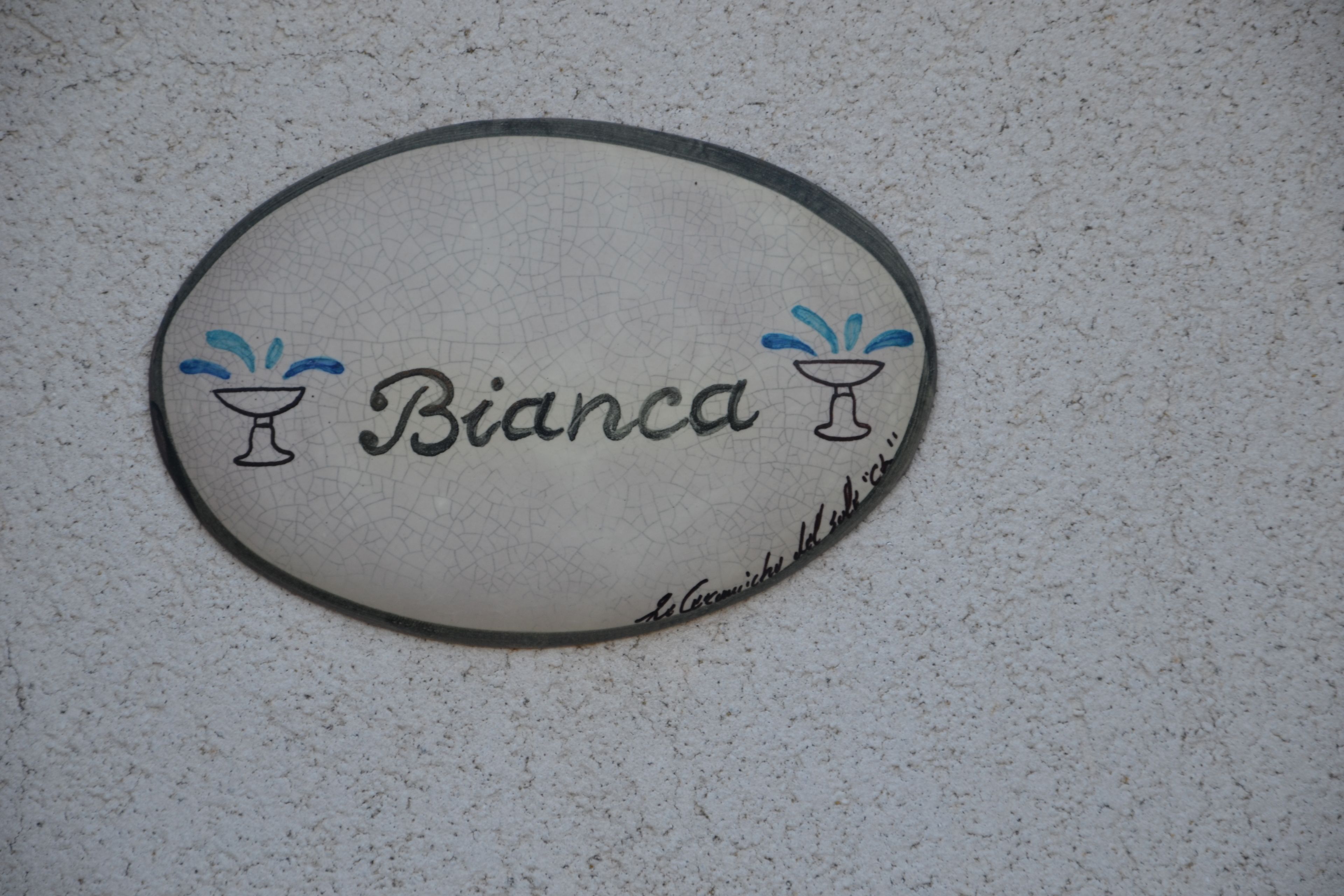 A circular sign with the name "Bianca" and two water glasses, one on each side.