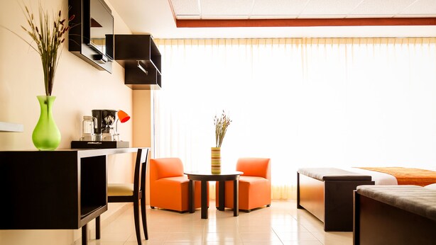 Un salon moderne avec un canapé, des fauteuils, une table basse et un téléviseur.