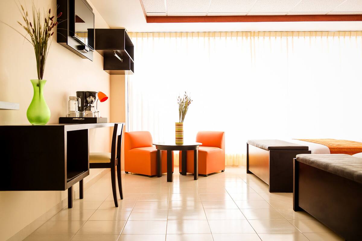 A modern living room with a sofa, chairs, a coffee table, and a TV.
