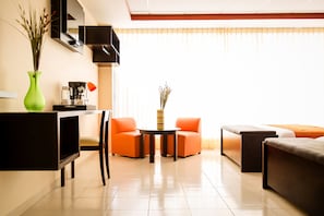 A modern living room with a sofa, chairs, a coffee table, and a TV.