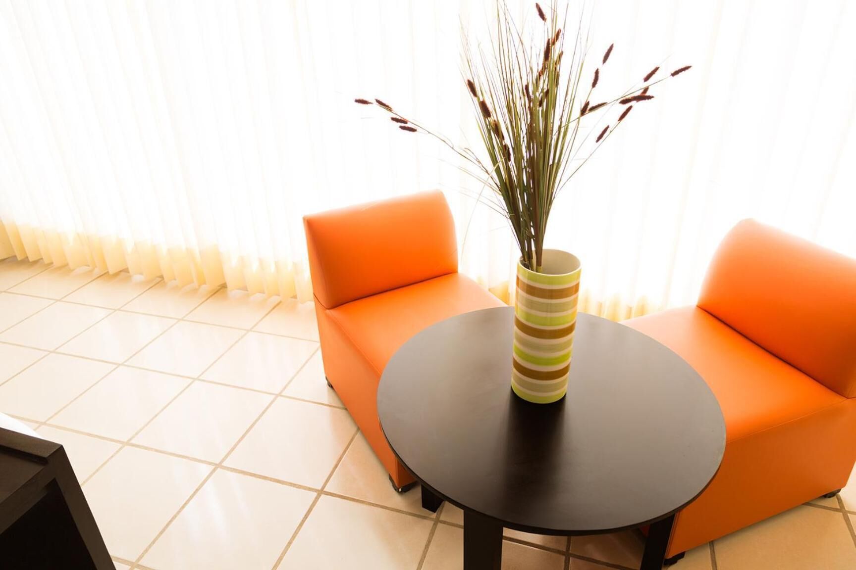 A room with a sofa and a round table, both in a vibrant orange color.