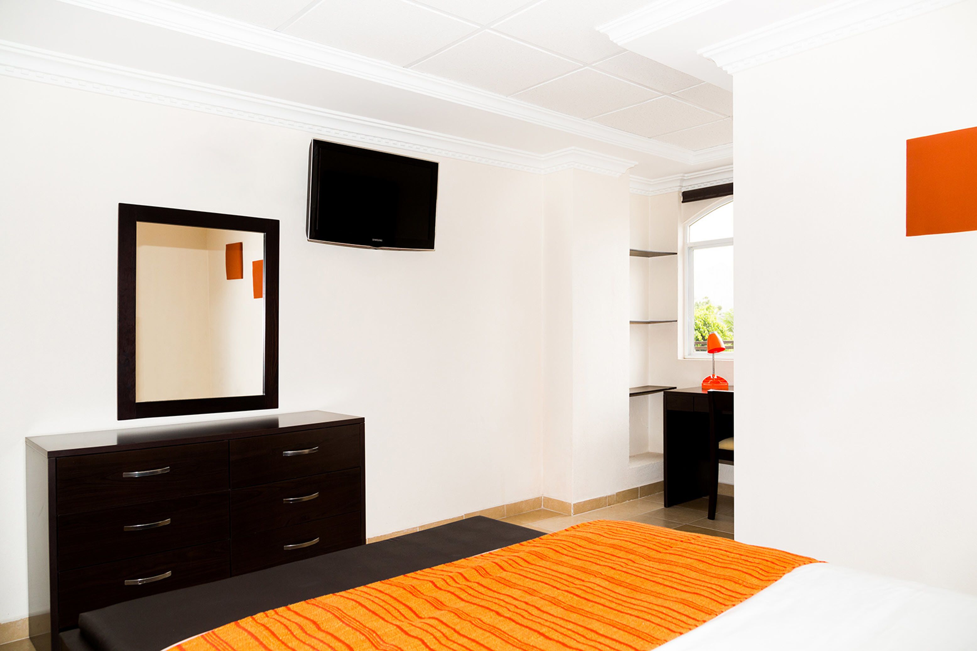 Habitación de hotel moderna con una cama grande, un aparador, un televisor de pantalla plana y una ventana con vistas a zonas verdes.