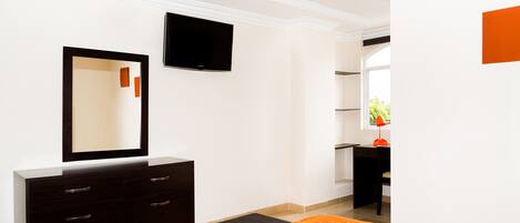 Habitación de hotel moderna con una cama grande, un aparador, un televisor de pantalla plana y una ventana con vistas a zonas verdes.