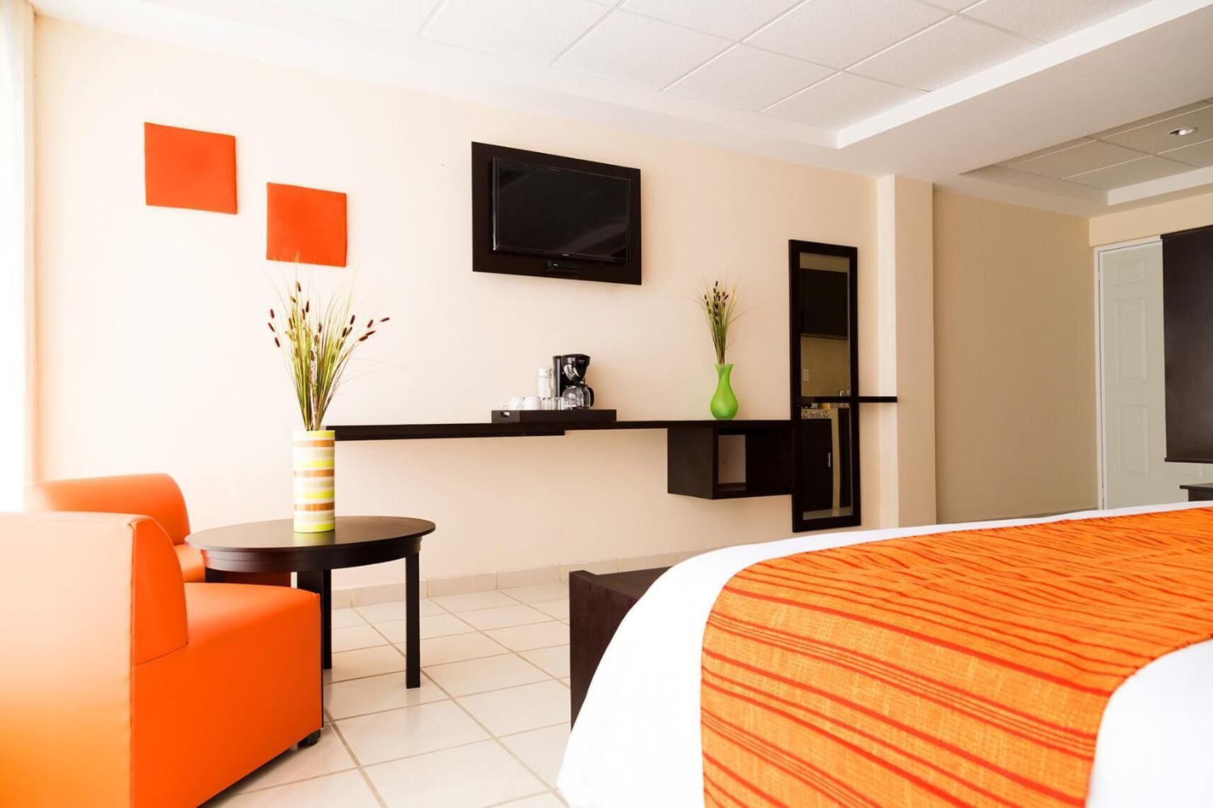A hotel room with a bed, a desk, a chair, a television, and a coffee machine.