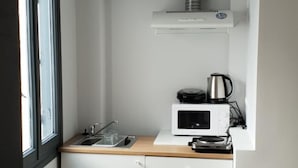 A compact kitchen with white cabinets, a microwave, a kettle, and a hanging rope. - athens.apartotel.2 (Athens)