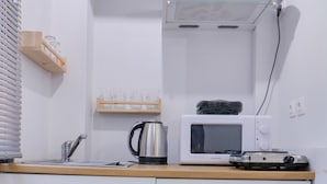 A kitchen with a microwave, kettle, and a wooden shelf with glasses. - athens.apartotel.2 (Athens)