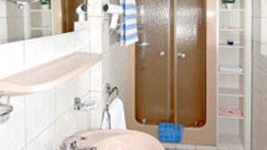 A bathroom with a sink, mirror, and shower. - Gasthof Zum Dorfkrug (Winterberg)