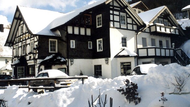 A traditional half-timbered building with multiple windows and a snow-covered roof. - Gasthof Zum Dorfkrug (Winterberg)