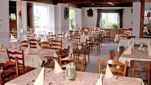 A restaurant with multiple tables and chairs, arranged in a spacious indoor setting with natural light from large windows. - Gasthof Zum Dorfkrug (Winterberg)