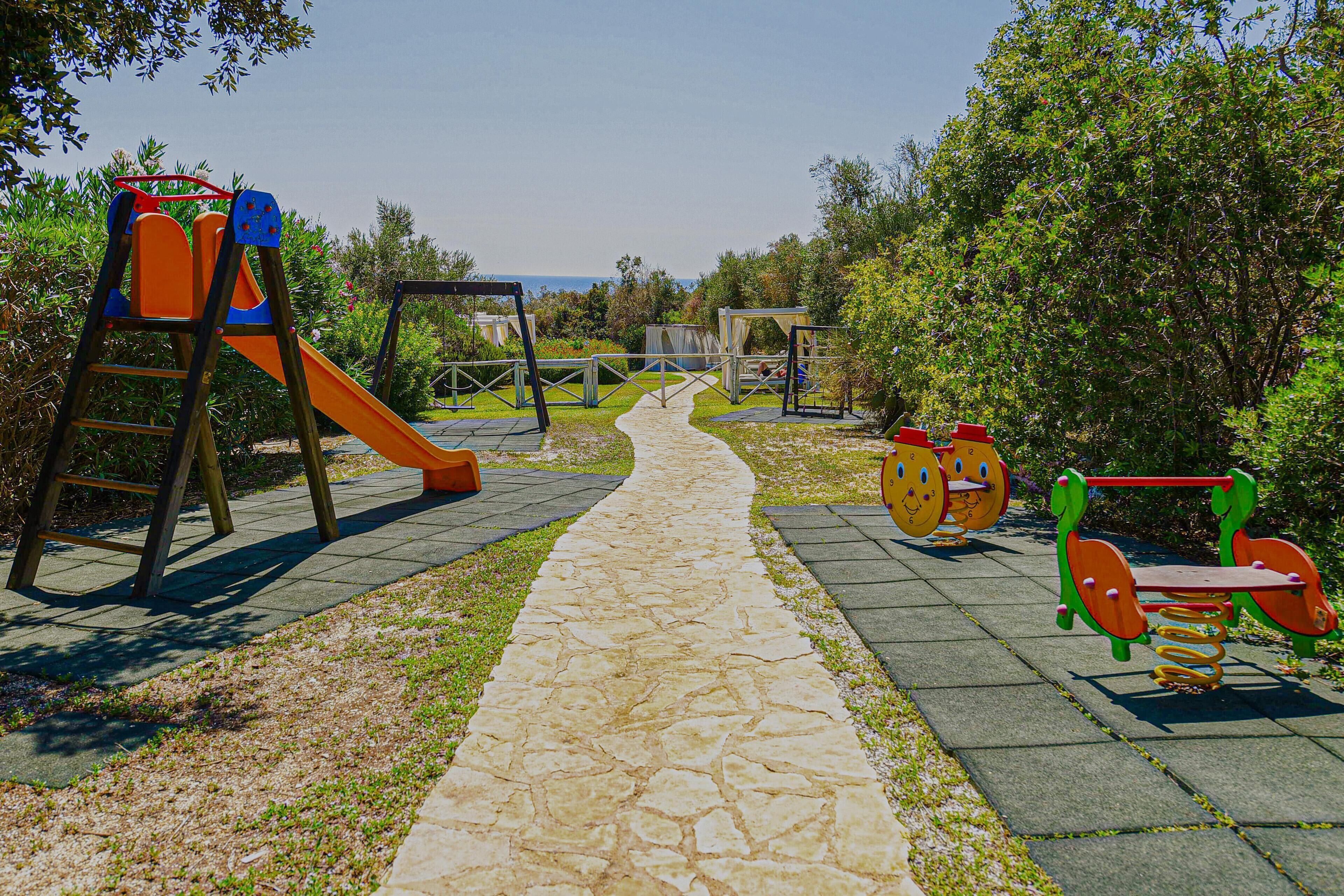 Un'area giochi con scivolo, altalene e attrezzature per esercizi fisici.