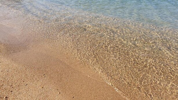 Une plage dégagée, avec des rochers visibles et une eau calme.