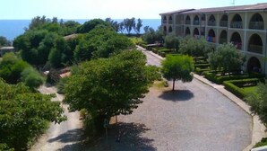 Une cour avec une zone pavée, entourée d’arbres et d’un bâtiment doté de nombreux balcons.