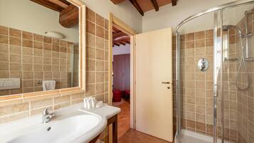 Un baño con un espejo grande, un lavamanos y una ducha con mampara de vidrio.