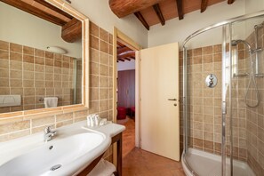 A bathroom with a large mirror, a sink, and a glass-enclosed shower. - Borgo di Celle (Città di Castello)