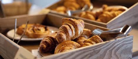A variety of pastries in wooden boxes, some with tongs.