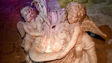 Scultura dettagliata di cherubini alati, su sfondo di muro in pietra.