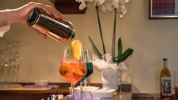 A person pouring a drink into a glass with an orange slice garnish.