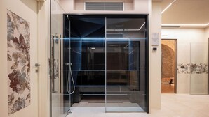 A modern elevator with glass doors, a visible control panel, and a stone wall in the background. - Borgo di Celle (Città di Castello)