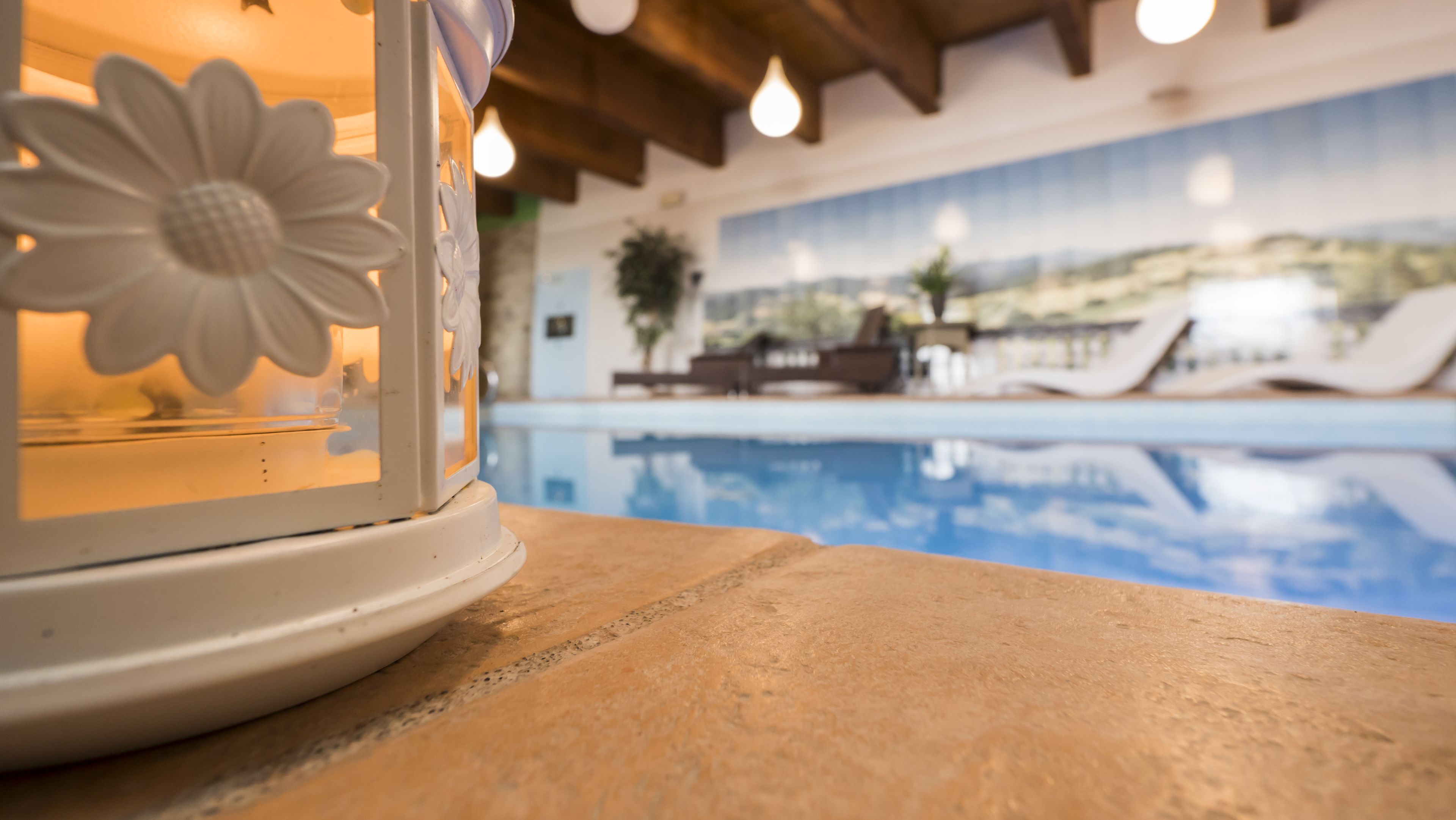 Un espace aménagé au bord de la piscine, avec une lampe décorative et une vue sur la piscine et les chaises longues.