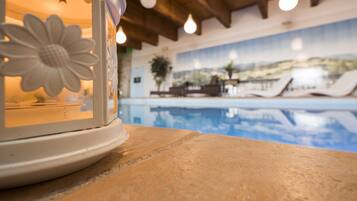 Un espace aménagé au bord de la piscine, avec une lampe décorative et une vue sur la piscine et les chaises longues.