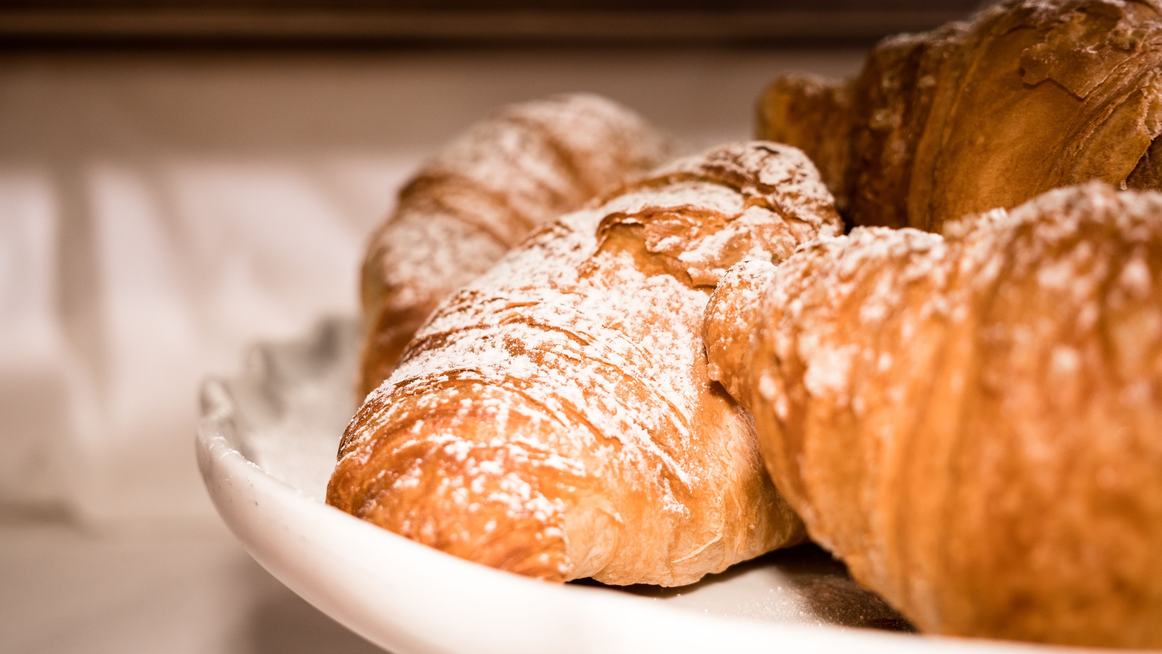 Uma travessa de croissants polvilhados com açúcar de confeiteiro.