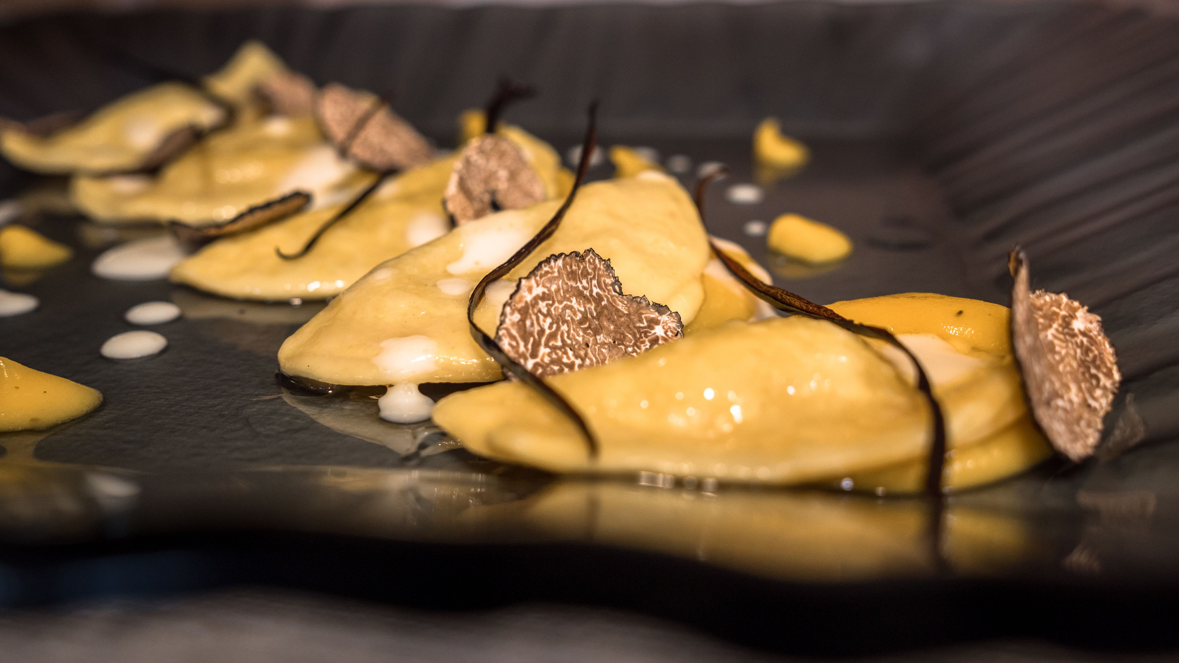 Gros plan d’une assiette de dessert avec une sauce au chocolat brillante, des morceaux de gâteau dorés et des copeaux de chocolat.