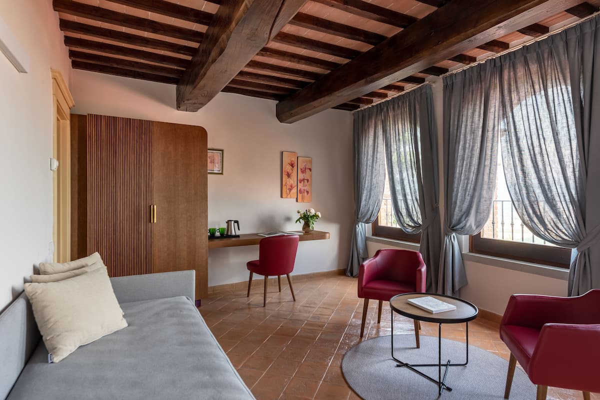 A cozy room with a sofa, red chairs, a small table, and a wooden wardrobe.