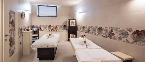 A room with two beds, a small desk, and a window.