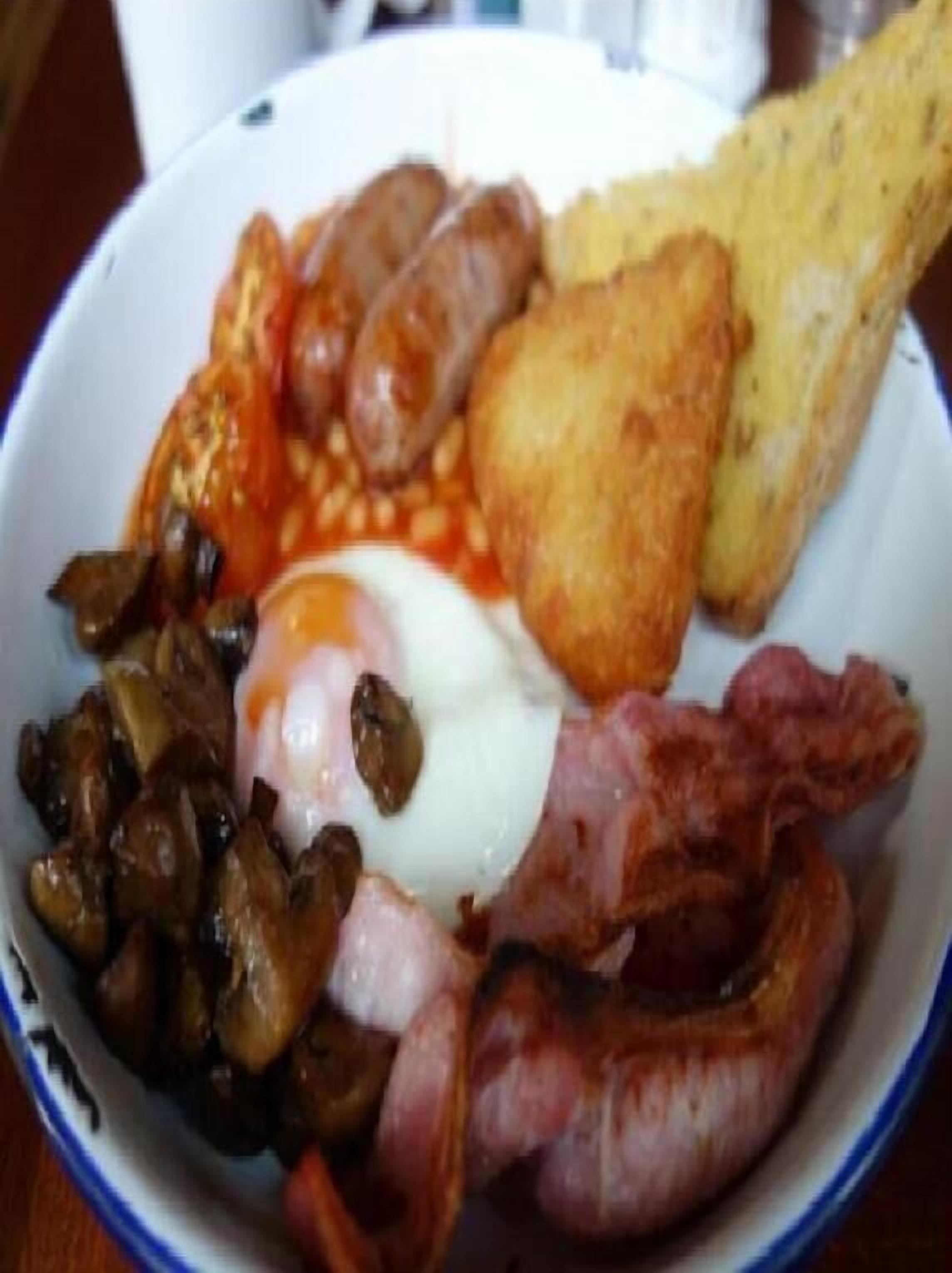 Une assiette de nourriture pour le petit-déjeuner comprenant des saucisses, des œufs, des champignons et des toasts.