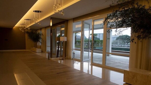 A spacious hotel lobby with a wooden floor, large windows, and a view of the outdoors. - Apartamento em Santo Amaro (São Paulo)