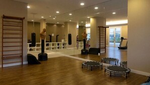 A gym with wooden flooring, mirrors, and exercise equipment including a punching bag and a treadmill. - Apartamento em Santo Amaro (São Paulo)