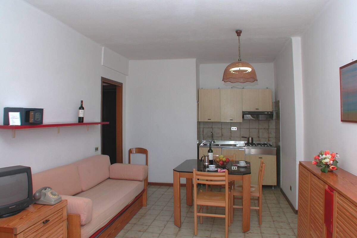 Um espaço compacto para viver, com cozinha americana, área de refeições e canto de estar.